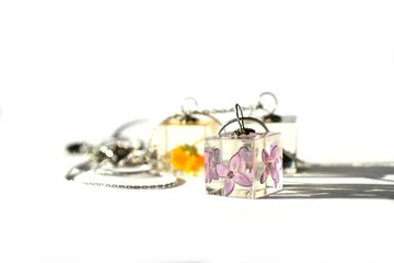 Beautiful epoxy resin jewelry with real dried flowers. Cube-shaped handmade pendant on a chain.