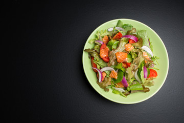Fresh salmon salad with tomatoes Fresh green onions and vegetables On a black background