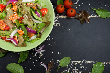 Fresh salmon salad with tomatoes Fresh green onions and vegetables On a black background