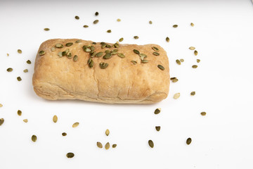 Italian ciabatta bread lies alone on a white background with pumpkin seeds