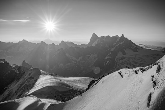 A black and white photo of the sun rising over Mont Blanc