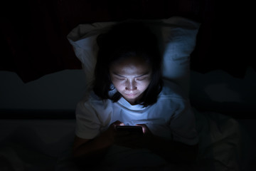 Asian woman play smartphone in the bed at night,Thailand people