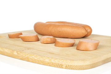 Group of two whole five slices of pork frankfurt sausage on bamboo cutting board isolated on white background