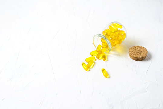 Glass Vial With Yellow Vitamins Tablets, Fish Oil, Omega Vitamin E. A Small Retro Jar With A Cork, Lies With Scattered Pills On A White Background. Flat Lay With A Copy Space.