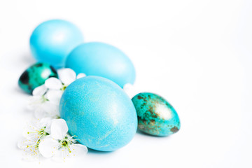 Obraz na płótnie Canvas Easter background. Blue easter eggs and white spring flowers on a white background close-up, soft focus 