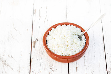 Homemade cottage cheese in a ceramic bowl on white old wooden table. Healthy food. Fresh dairy products. Top view
