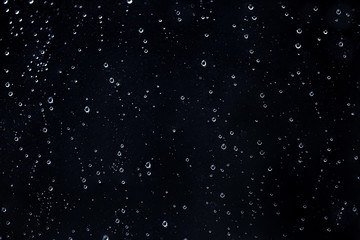 Rain water drops on a black dramatic window glass. Autumn  depression background. Rain pattern.