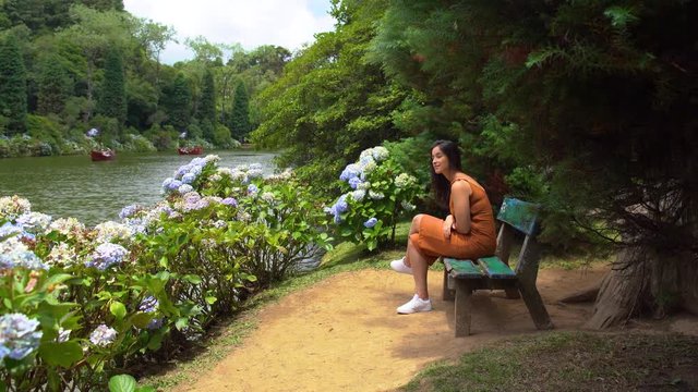 Woman at Lago Negro black lake park in Gramado Brazil, seated at a bench in a park thinking