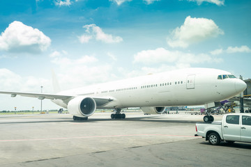 Fototapeta na wymiar modern passenger or big cargo airplane parking at terminal gate of international airport on a cloudy blue sky background