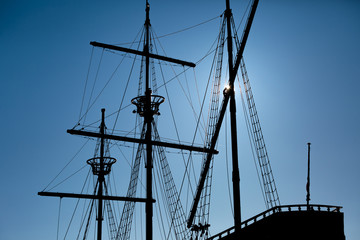 Sailing masts of an antique ship on blue sky background