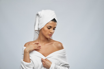 Woman in bathrobe touching naked shoulder.