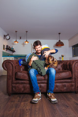 Naklejka premium Father's day, family and parenthood concept. Young father playing with little kids at home.