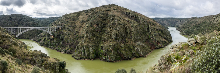 Panoramic photography of the area known as the Arribes del Duero in Zamora, Spain. The metal arch bridge known as Puente Requejo is seen - obrazy, fototapety, plakaty