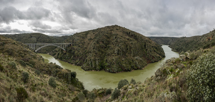 Panoramic photography of the area known as the Arribes del Duero in Zamora, Spain. The metal arch bridge known as Puente Requejo is seen
