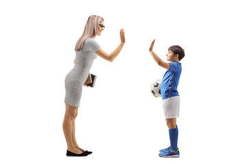 Boy with a soccer ball gesturing high five with a young woman
