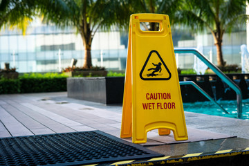 Caution! Wet floor! Danger sign by the swimming pool