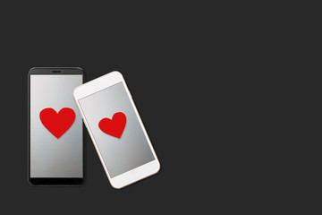 Valentine day concept, two smartphones vith red heart shape on screen, isolated on dark background