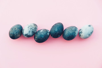 Natural dyed blue colored eggs on pastel pink background, top view.