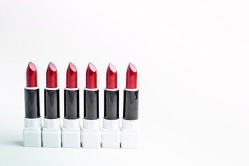 Six open rods of red lipstick are placed on a light background. Colorful decorative cosmetics.