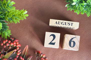 August 26, Number cube design with flower on brown lether background.
