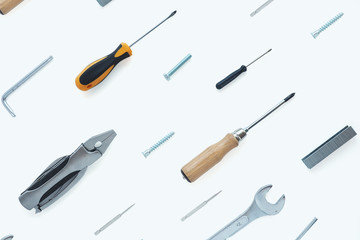 .A pattern of tools: nippers, screwdrivers, keys, bolts, staples for a stapler, self-tapping screws, nut on a white background..