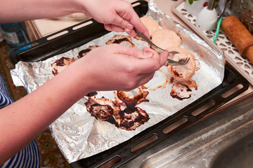 Girl raises cutlet with a fork. Dietary hot chicken cutlets from the oven on a baking sheet on a table in the kitchen, view from above, close-up. home cooking