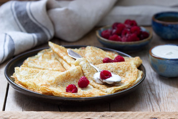 Pancakes served with sour cream, raspberries and honey. The traditional dish on Carnival and Maslenitsa.
