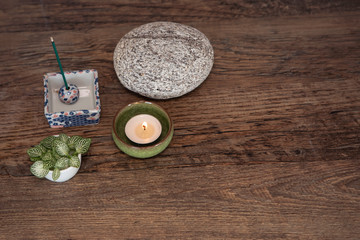 Spiritual deco arrangement with burning candle, incense sticks, round stone and fresh leaves from above. Mindfulness, meditation concept. Zen style background with copy space. 