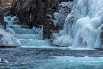 A frozen waterfall with ice in a blue and white color in winter. Iceland
