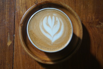 latte art on cappucino and coffee with the wooden saucer.
