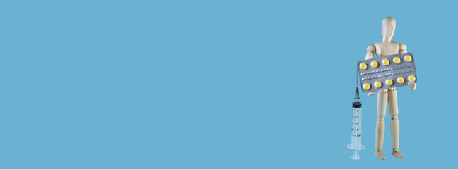 Wooden toy figure with pills on blue trendy background. Long wide banner