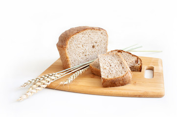 Rye and wheat bread. A loaf of bread on a cutting board with ears of wheat and a handful of wheat flour. Food