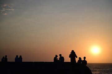Fototapeta na wymiar silhouette of people, couples taking selfie photos of the sunset and the sea