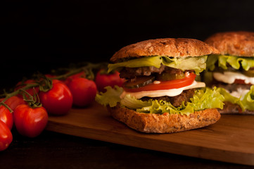 Russian burgers on a wooden Board with tomatoes on a dark background