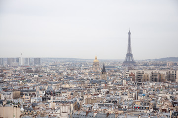 Naklejka premium Scenic view over the Paris roofs with Eiffel Tower in background on a hazy day with the overcast sky.