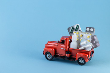 Toy car truck with pills on a blue background. Various capsules, tablets and medicine on toy car transportation. Medicine concept. Copy space for your design.
