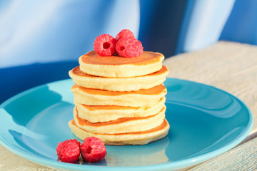 a stack of freshly baked pancakes decorated with raspberries. copcept delicious breakfast