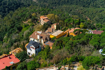 Fototapeta na wymiar Stone houses on the hill surrounded with trees. Small vilage near Barcelona, Spain