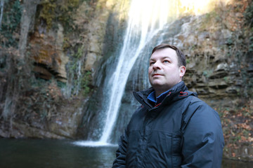 Man posing on background of waterfall