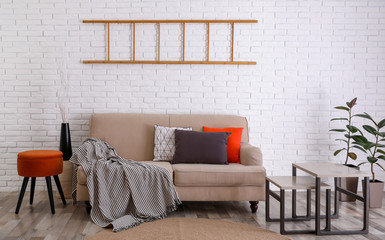 Soft pillows on sofa near white brick wall at home