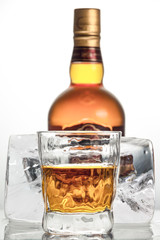 Glass with an alcoholic drink on the background of a large block of rectangular ice