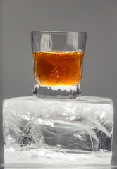 Glass with an alcoholic drink on a large piece of ice