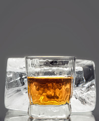Glass with an alcoholic drink on the background of a large block of rectangular ice