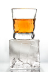 Glass with an alcoholic drink on a large piece of ice