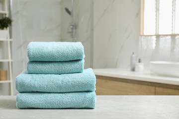 Stack of clean towels on table indoors. Space for text