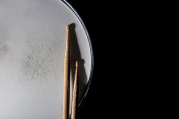 Drum stick and drum on black table background, top view, music concept