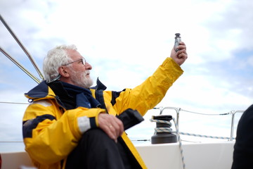 White bearded sailing senior, experienced skipper is checking the wind force, knots on a sailboat...