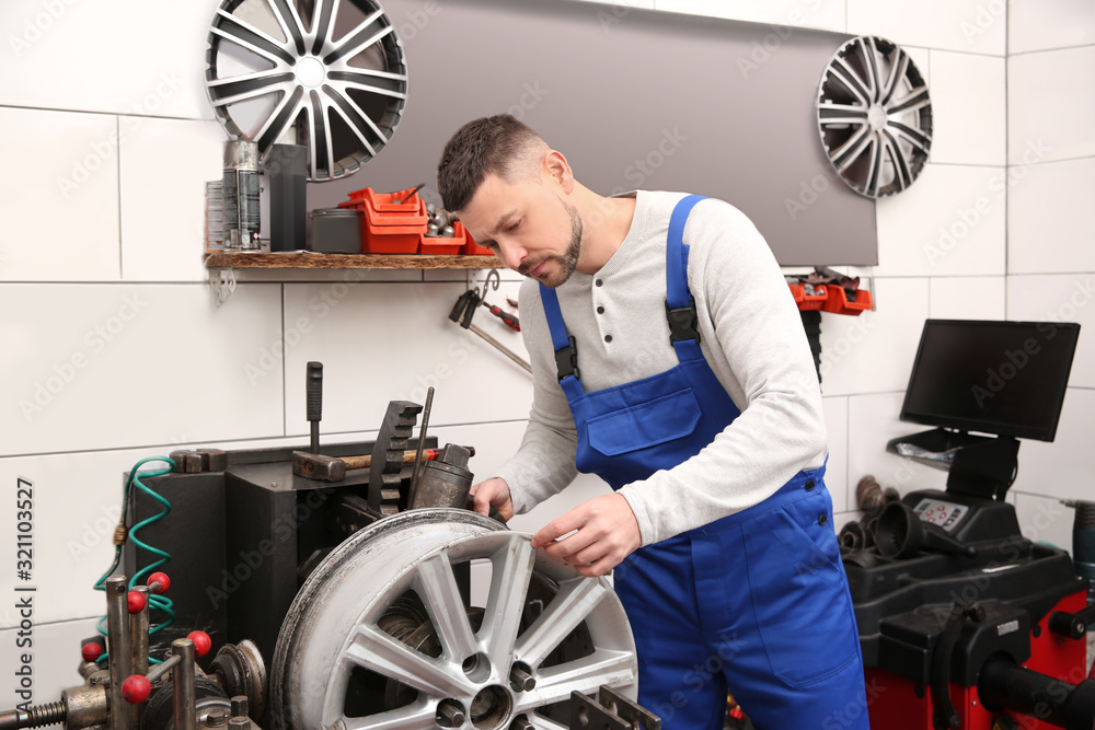 Wall mural Mechanic working with car disk lathe machine at tire service