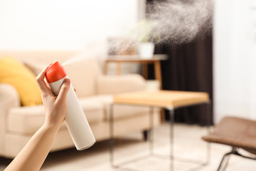 Woman spraying air freshener at home, closeup