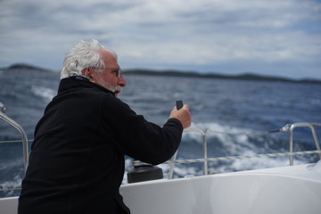 White bearded sailing senior, experienced skipper on a sailboat